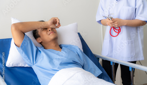 Tableau sur toile Aching Discomfort: A young male patient winces in pain, seeking relief from a compassionate nurse in a sterile hospital setting