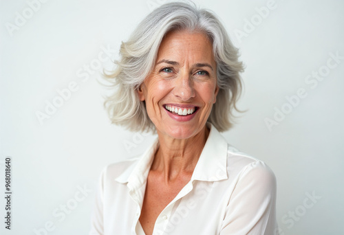 Close-up portrait of a graceful, silver-haired woman in a white blouse, showcasing elegance and warmth.