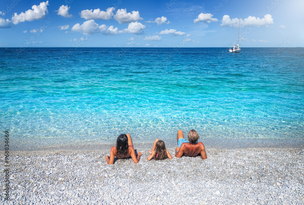 Rear view of a family lying on a beach with turquoise sea for the summer holiday vacations with copy space