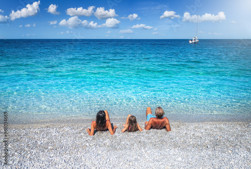 Obraz na płótnie Rear view of a family lying on a beach with turquoise sea for the summer holiday vacations with copy space w salonie