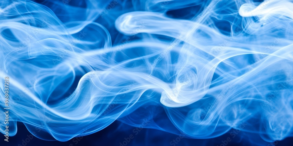 Fototapeta premium A delicate blue smoke curls and undulates, creating an enchanting visual effect on a dark background, evoking a sense of tranquility