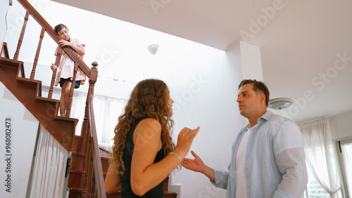 Stressed and unhappy young girl watch her parent arguing from the stair. Domestic violence at home and traumatic childhood develop to depression and anxiety. Unhealthy family concept. Synchronos photo