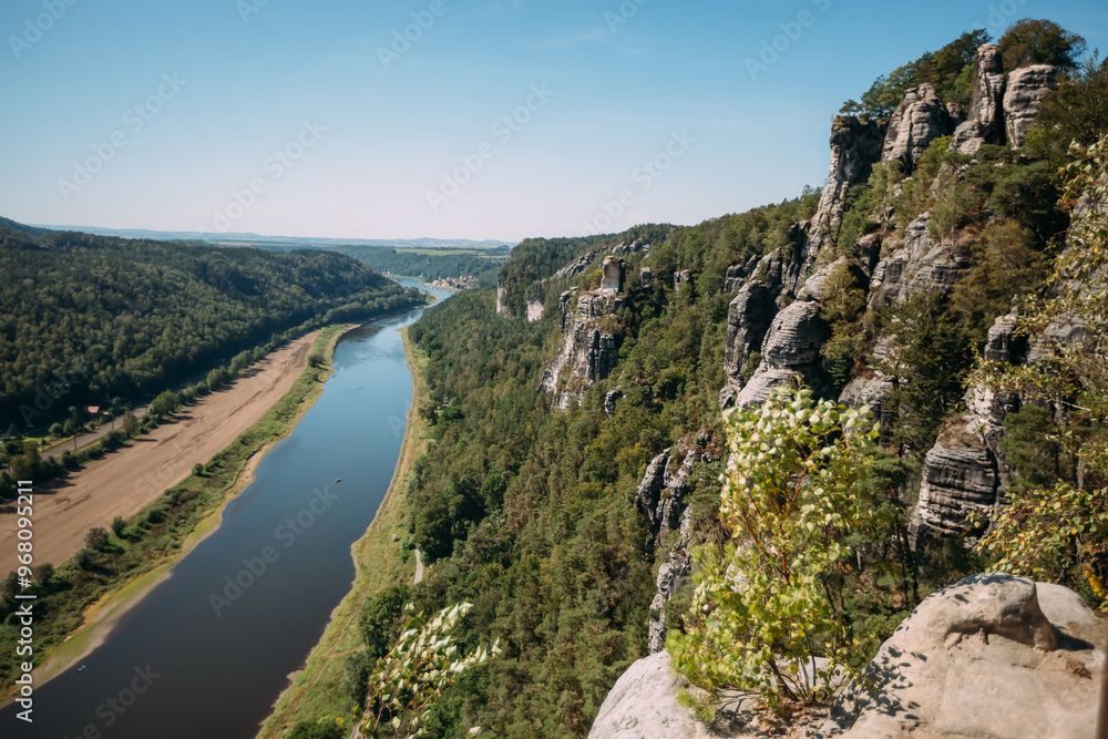 Scenic view of a winding river through a lush forested valley with rocky cliffs under a clear blue sky, capturing the natural beauty and landscape of the region Scenic view of a winding river through a lush forested valley with rocky cliffs under a clear blue sky, capturing the natural beauty and landscape of the region