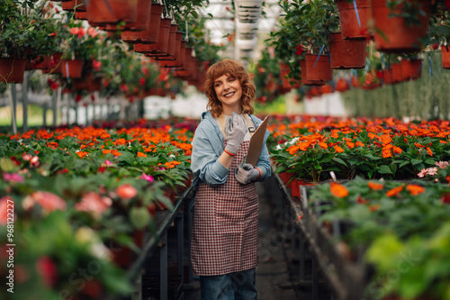 Young florist enjoying flower galore in her modern greenhouse.