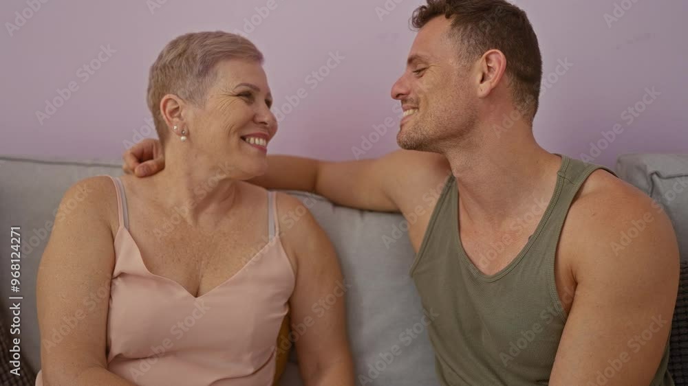 Mother and son smiling and looking at each other lovingly while sitting on a sofa indoors at home showcasing a warm family bond and affectionate relationship Mother and son smiling and looking at each other lovingly while sitting on a sofa indoors at home showcasing a warm family bond and affectionate relationship