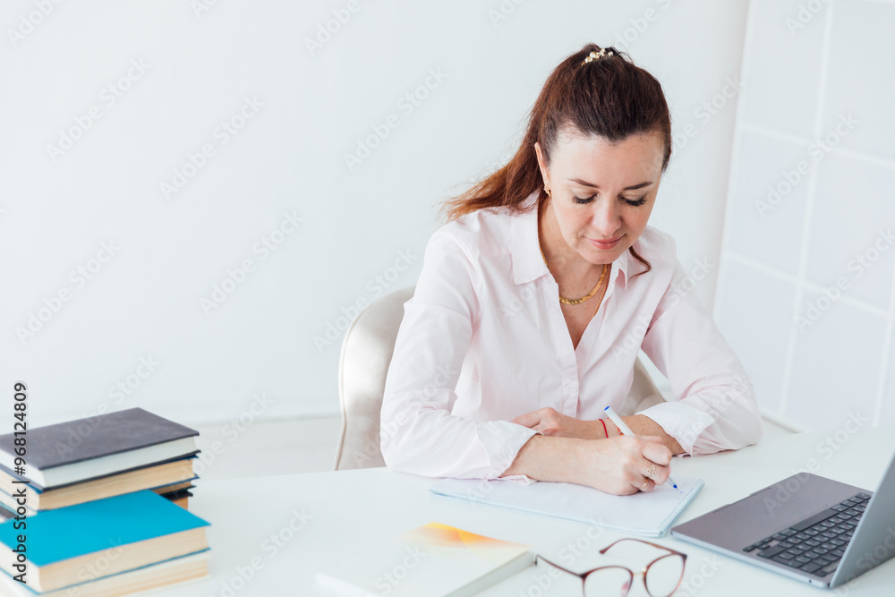 Beautiful business woman with online laptop at desk in office Beautiful business woman with online laptop at desk in office