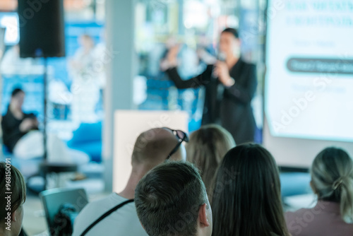 Speaker delivering a presentation to an engaged audience during a professional business seminar. Focused on sharing knowledge and fostering interaction.