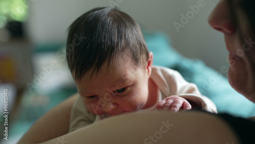 Mother holding newborn baby close, both looking calm and serene. gentle embrace and warm home setting highlight the loving bond between mother and child, creating a peaceful atmosphere
