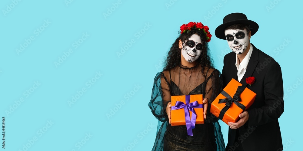 Young couple dressed for Mexico's Day of the Dead (El Dia de Muertos) holding gifts on light blue background with space for text Young couple dressed for Mexico's Day of the Dead (El Dia de Muertos) holding gifts on light blue background with space for text