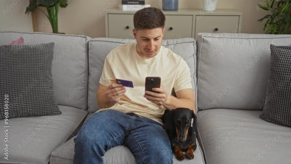 Young hispanic man at home sitting on a couch in the living room, holding a smartphone and a credit card, with a dachshund dog next to him, engaged in online shopping. Young hispanic man at home sitting on a couch in the living room, holding a smartphone and a credit card, with a dachshund dog next to him, engaged in online shopping.