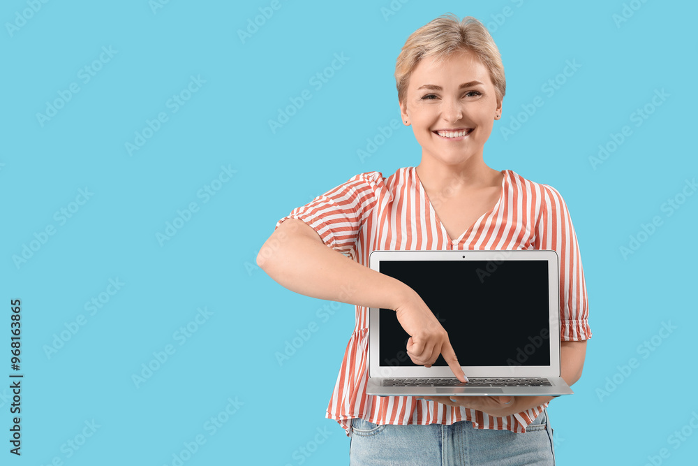 Happy young female programmer pointing at laptop on blue background Happy young female programmer pointing at laptop on blue background