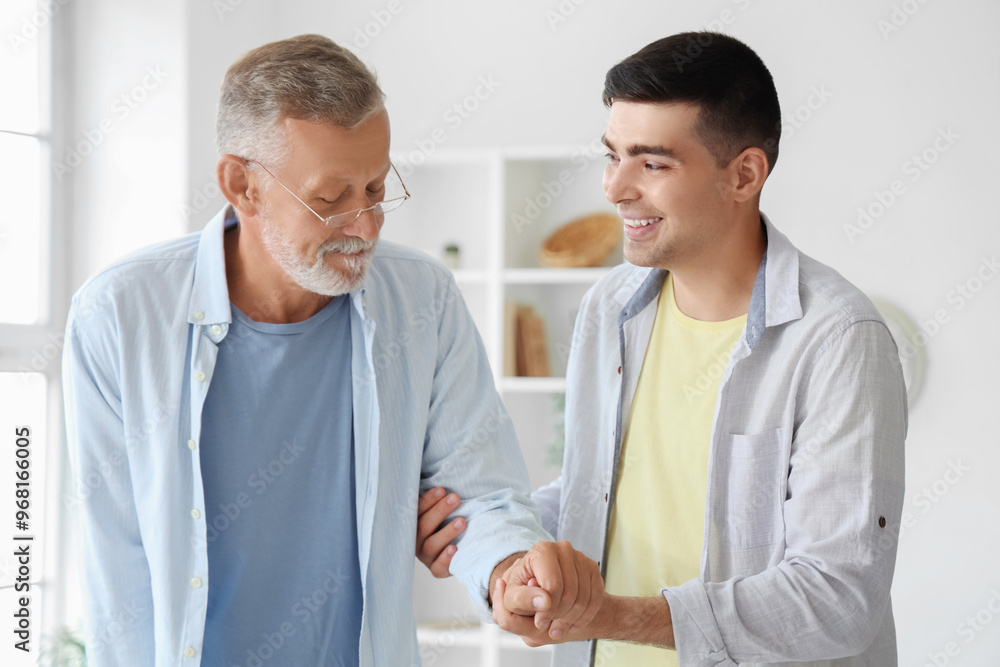 Obraz premium Young man helping his father to walk at home