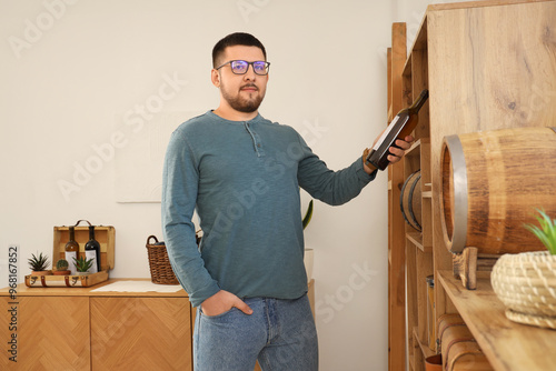 Young sommelier with bottle...