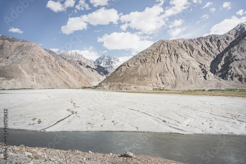 A panorama of the mountain landscape of the Wakhan Corridor and the Panj River in the valley with rocky mountain peaks with snow and glaciers in the background, in Tajikistan in Pamir photo