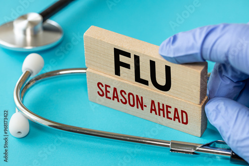 Flu Season ahead symbol. Flu Season ahead concept word on wooden blocks. Doctor's hand. Blue background and stethoscope. Medicine and Flu Season ahead concept. close up