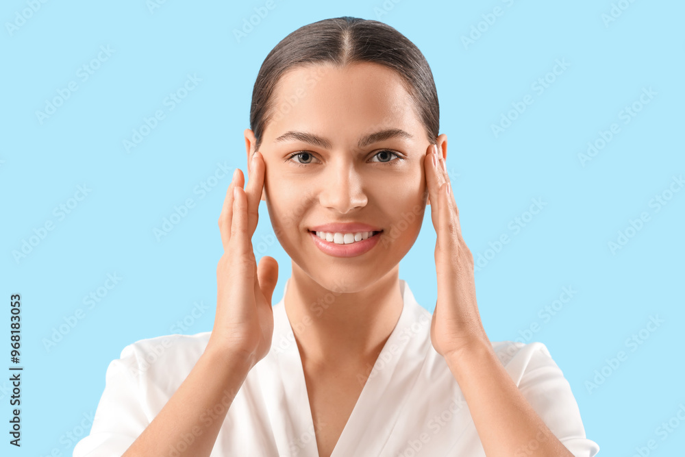 Beautiful young woman massaging her face on blue background, closeup Beautiful young woman massaging her face on blue background, closeup