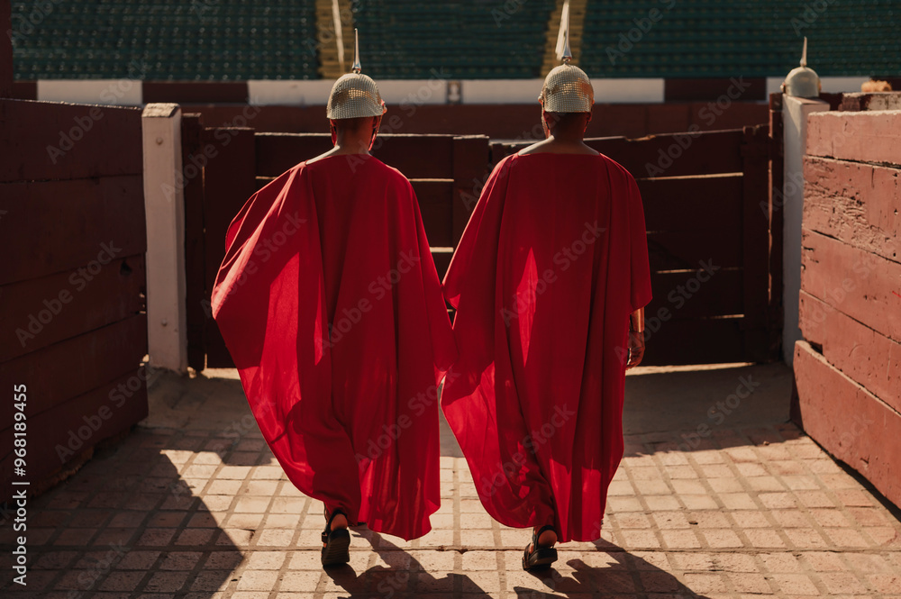 two men from behind dressed as Roman guards entering a bullring two men from behind dressed as Roman guards entering a bullring