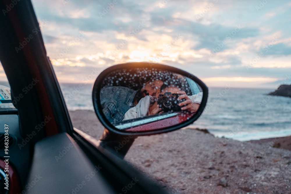 Photographer capturing a scenic seascape in car side mirror Photographer capturing a scenic seascape in car side mirror