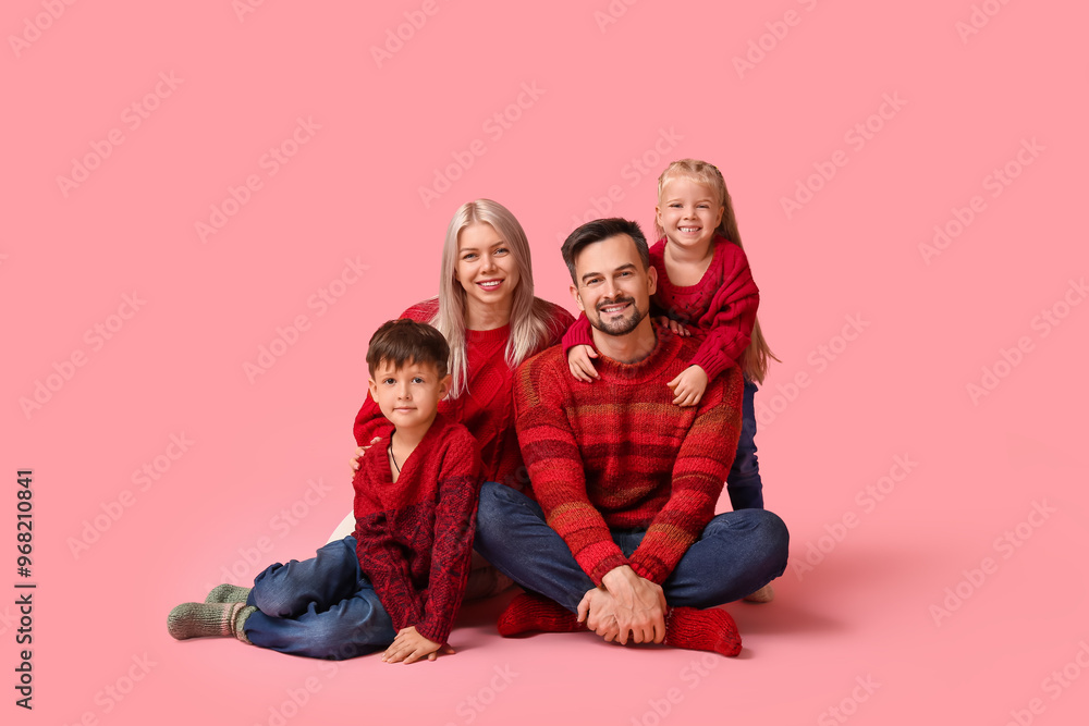 Happy family with children in winter clothes sitting on pink background Happy family with children in winter clothes sitting on pink background