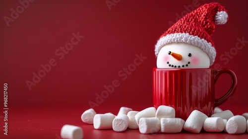 Cheerful snowman decoration in a red mug surrounded by marshmallows on a fest...
