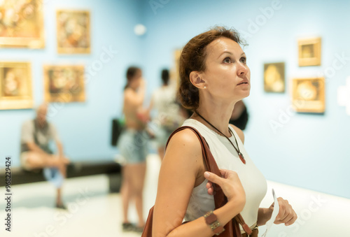 Portrait of young beautiful woman looking at pictures and amaze in museum, holding guide book Free Download Portrait of young beautiful woman looking at pictures and amaze in museum, holding guide book - GFXLoad