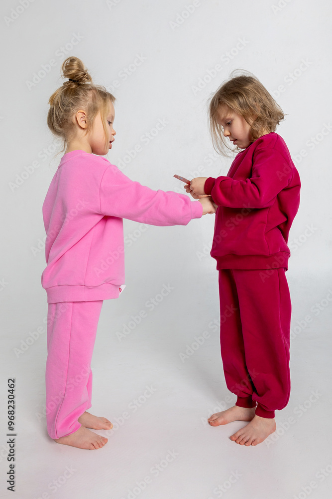 Two funny cute girls playing and having fun. Children with smiles and funny emotions on a light background. Vertical photo. High quality photo Two funny cute girls playing and having fun. Children with smiles and funny emotions on a light background. Vertical photo. High quality photo