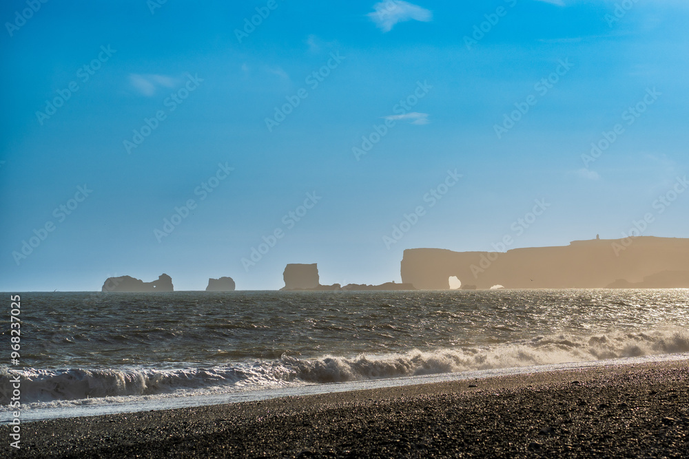 Obraz premium The dramatic Reynisfjara Beach features black volcanic sands and towering basalt sea stacks rising from the wild Atlantic Ocean in Iceland