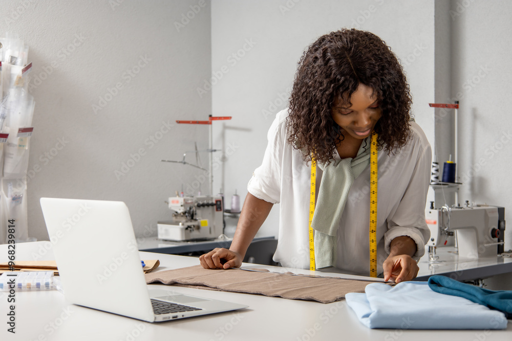 Woman fashion designer sewing clothing with online sketches on laptop Woman fashion designer sewing clothing with online sketches on laptop