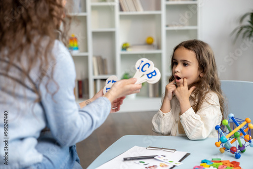 Speech therapist showing letters to a girl while having a training session