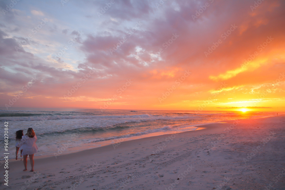 Beautiful peaceful pink orange sunset in Panama City Beach Florida and 2 girls frolicking in the sand Beautiful peaceful pink orange sunset in Panama City Beach Florida and 2 girls frolicking in the sand
