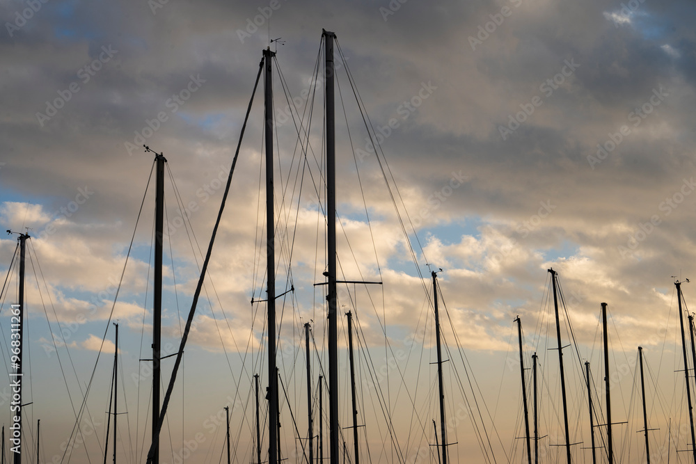 Fiery contrasting clouds in the blue sky, at sunset, through the masts of sailing yachts. Fiery contrasting clouds in the blue sky, at sunset, through the masts of sailing yachts.