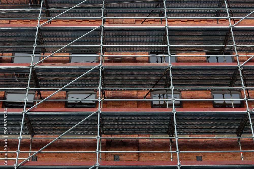 Red Brick Building Facade Covered with Scaffolding for Renovation Red Brick Building Facade Covered with Scaffolding for Renovation