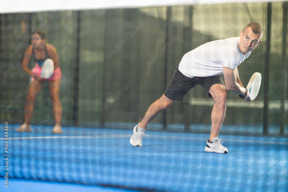 Obraz premium Young woman and young man playing doubles tennis on tennis court