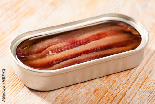 Canned anchovy fillet in oil served on wooden table photo