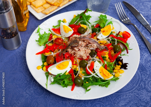 Catalonian xato salad with cod, chopped eggs, corn and onions on a table in a restaurant photo