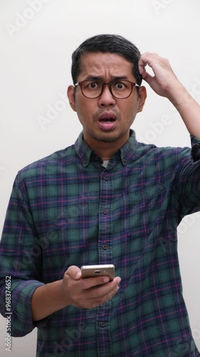 A man holding phone scratching head showing confused gesture photo