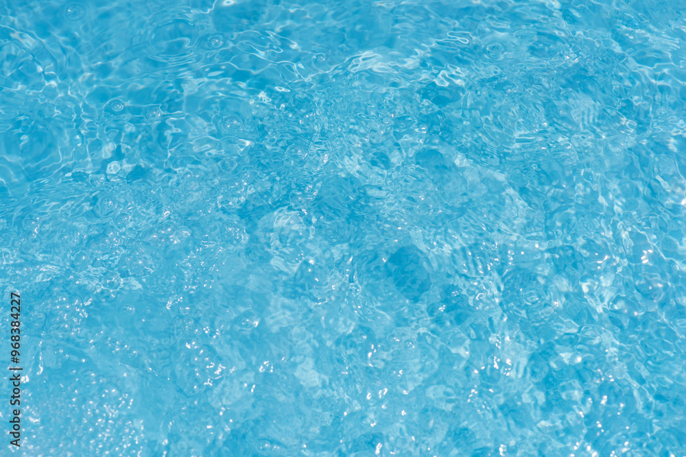 Blue water with ripples on the surface. Defocus blurred transparent blue colored clear calm water surface texture with splashes and bubbles. Water waves with shining pattern texture background. Blue water with ripples on the surface. Defocus blurred transparent blue colored clear calm water surface texture with splashes and bubbles. Water waves with shining pattern texture background.