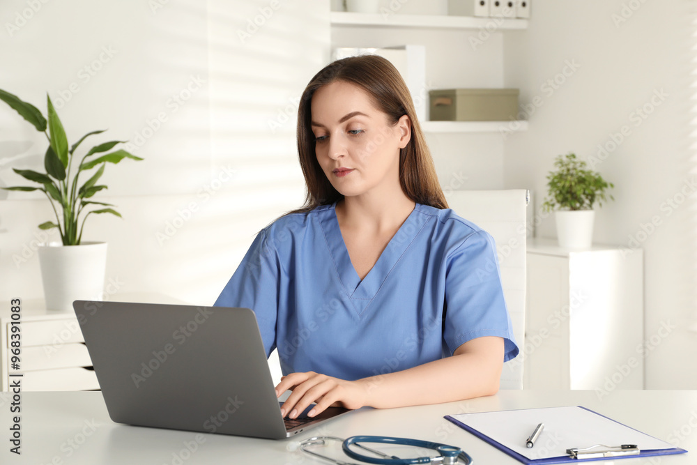 Young nurse working with laptop at desk in hospital Young nurse working with laptop at desk in hospital