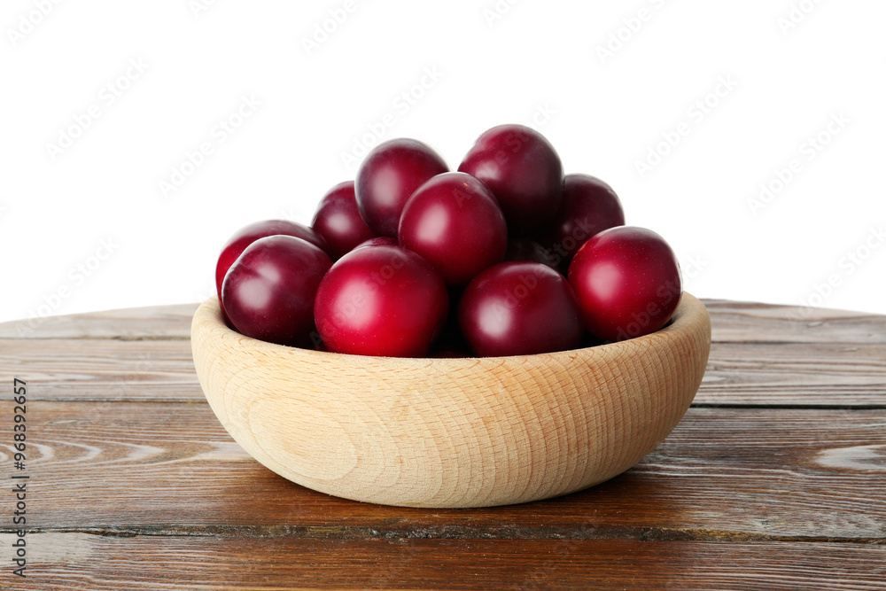 Fresh ripe plums in bowl on wooden table against white background Fresh ripe plums in bowl on wooden table against white background