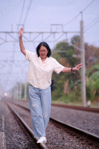 A woman walks on old railroad tracks; trying to keep her balance photo