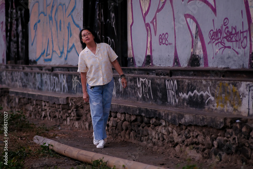 Woman walking alone behind a dirty vandalized old storage building