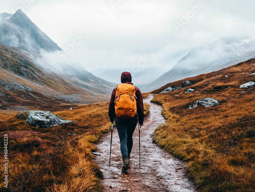 A Woman Hiking In the Mountains in Misty Weather. She Is Wearing Outdoor Gear Such As a Yellow Backpack and fitted pants. photo