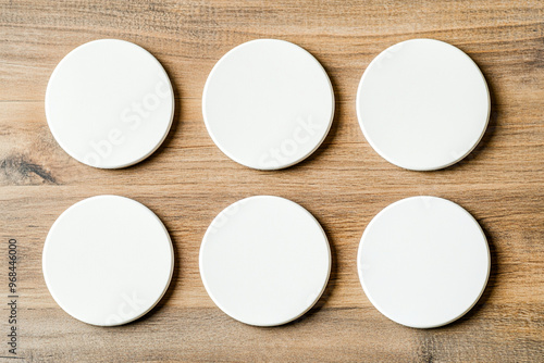 Blank round coasters arranged neatly on rustic wooden table create minimalist aesthetic. These coasters are perfect for protecting surfaces while adding touch of simplicity to any setting