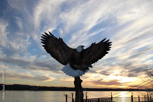 Statue of a bald eagle with a sunset over the Columbia River in the background