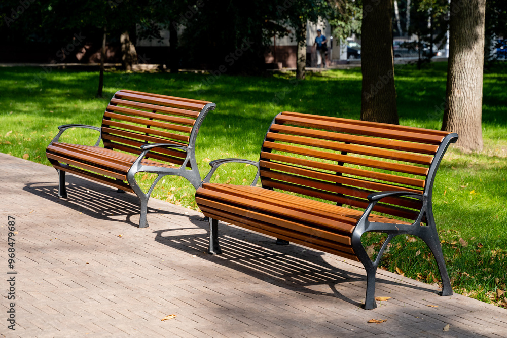The Elegant Wooden Park Benches are beautifully situated under the warm sunlight, nestled in a lush and vibrant green park, offering a cozy retreat The Elegant Wooden Park Benches are beautifully situated under the warm sunlight, nestled in a lush and vibrant green park, offering a cozy retreat