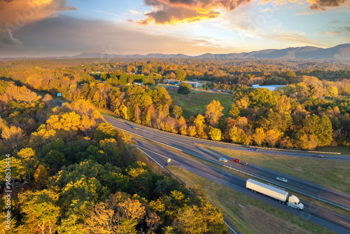 Wide multilane highway road in USA Appalachian mountains with fast driving semi trucks. Above view of American transportation infrastructure