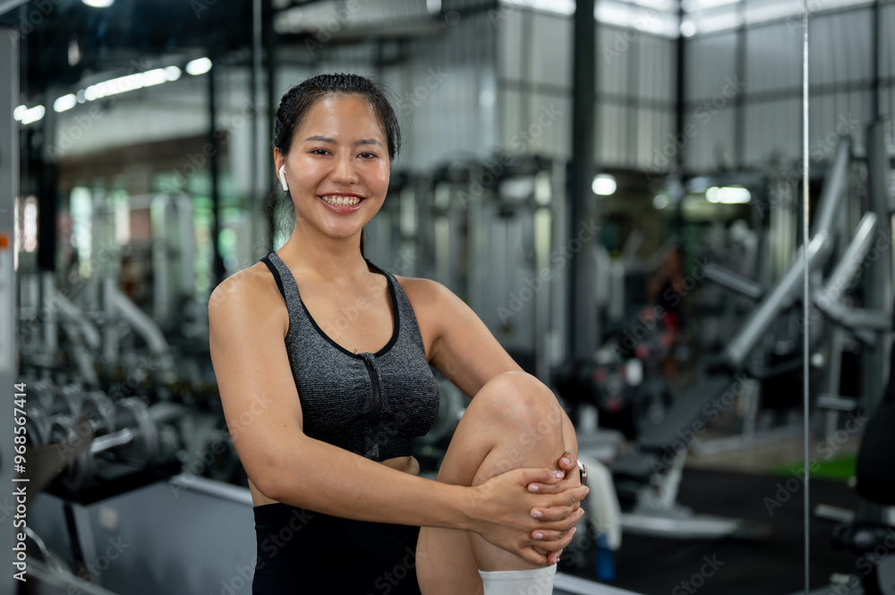 Fototapeta premium An athlete Asian woman in sportswear is stretching her body before workout at the gym.