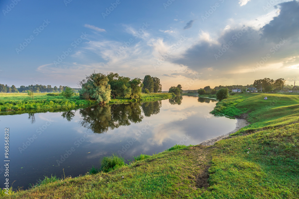 Obraz premium A calm river with a reflection of the sky and trees
