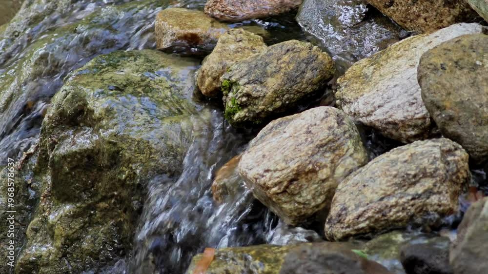 Clear water flows from the mountains to form small waterfalls between the rocks. Clear water flows from the mountains to form small waterfalls between the rocks.