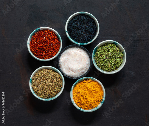Traditional oriental spices in ceramic bowls. black cumin seed, ground red pepper, dried mint, himalayan ​​salt.